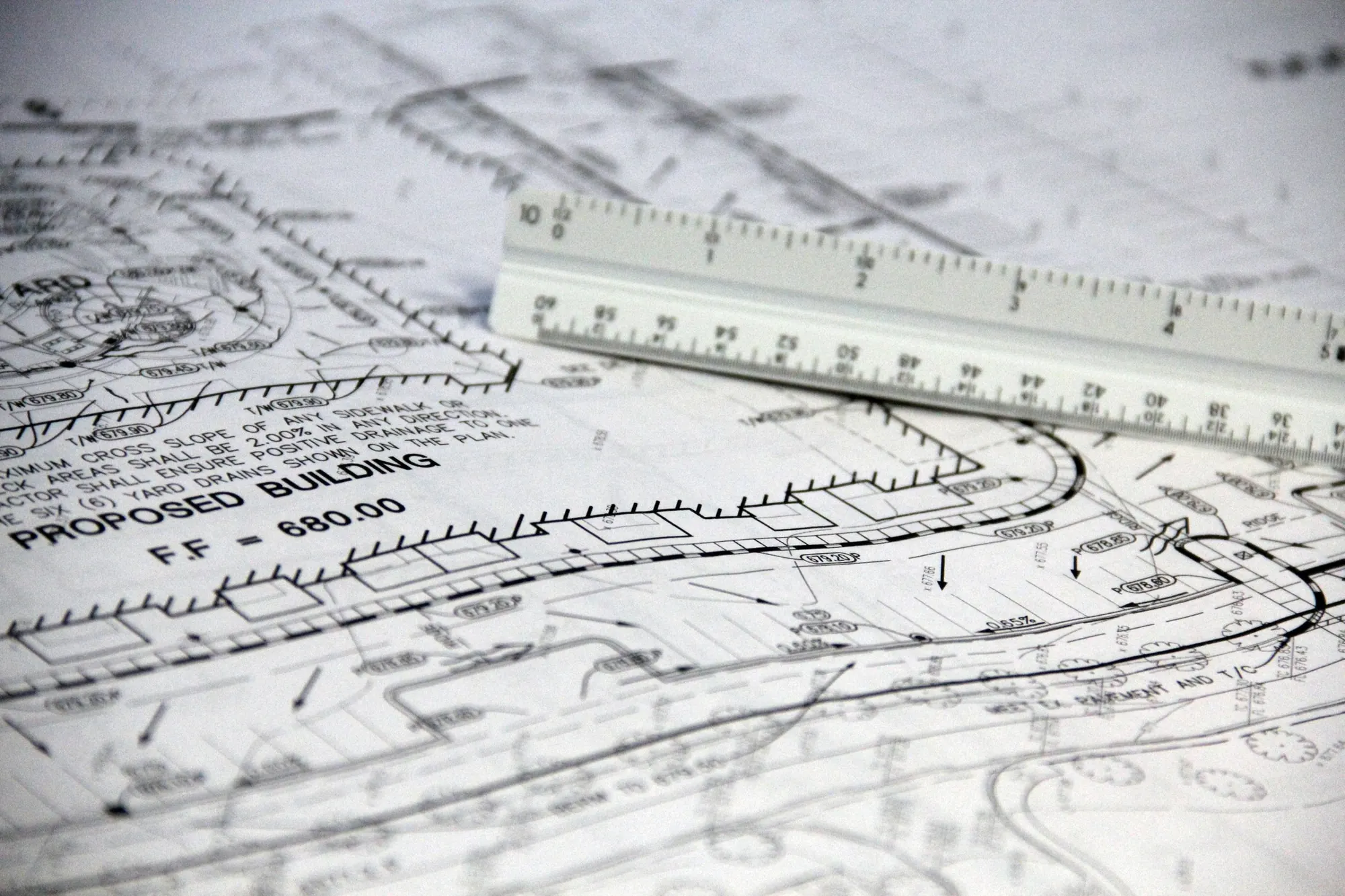 A residential site plan marked proposed building, with an architect scale ruler resting on the drawing
